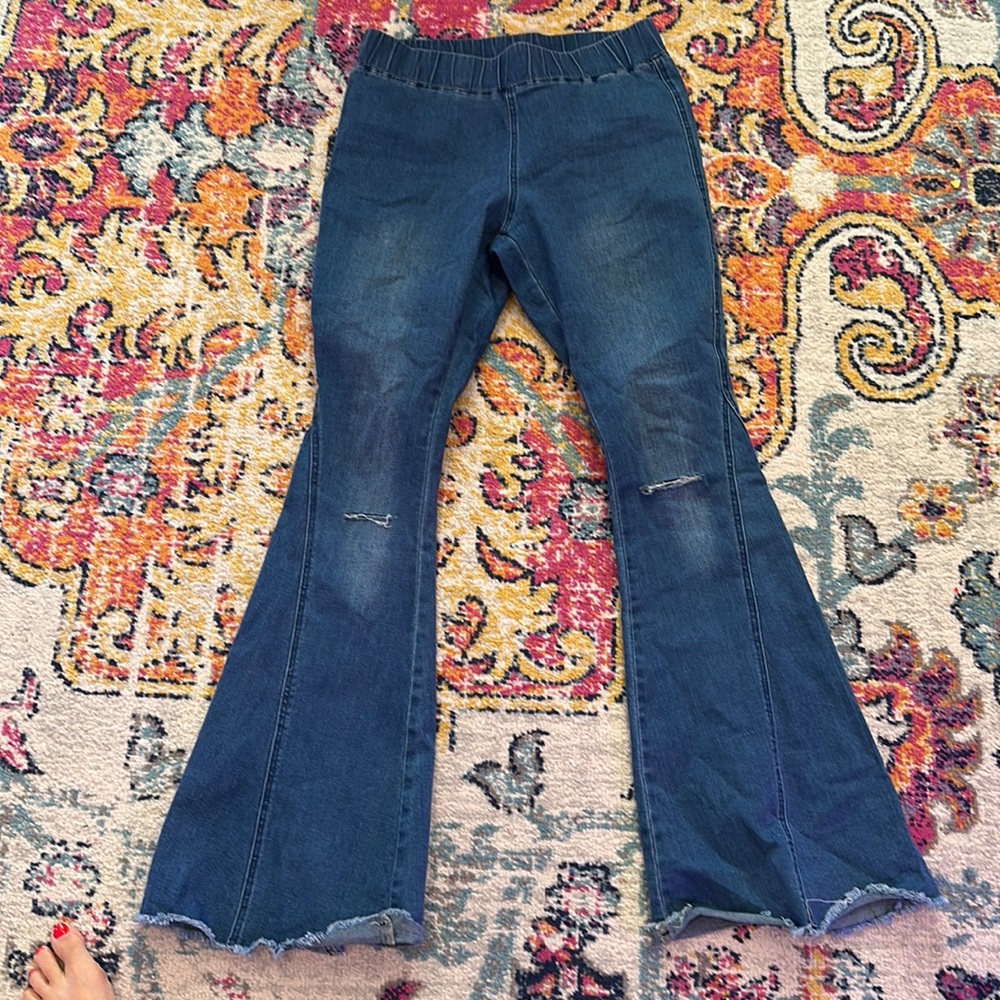 Stretchy pull on bell bottom jeans with rip and frayed hem flare
